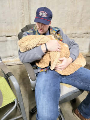 Man Holding Stuffed Animalin Chair Wallpaper