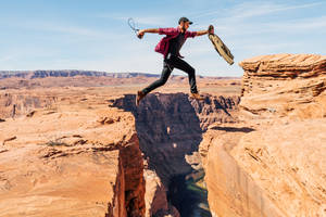 Man Jumping On Rock Formation Wallpaper