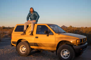 Man Seatedon Yellow Isuzu Amigoat Dusk Wallpaper