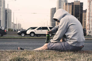 Man Sitting Alone On Roadside Wallpaper