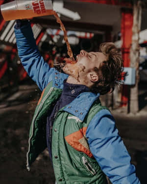 Man Spilling Drink Outdoors Wallpaper