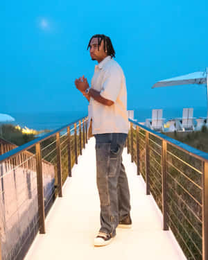 Man Standingon Beachside Walkwayat Dusk Wallpaper