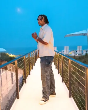 Man Standingon Beachside Walkwayat Dusk Wallpaper