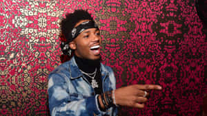 Metro Boomin Laughing Against Patterned Backdrop.jpg Wallpaper