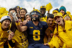 Michigan Football Player Celebratingwith Fans Wallpaper