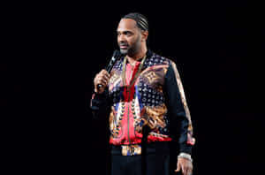 Mike Epps Strikes A Thoughtful Pose Against A Textured Grey Wall Backdrop. Wallpaper