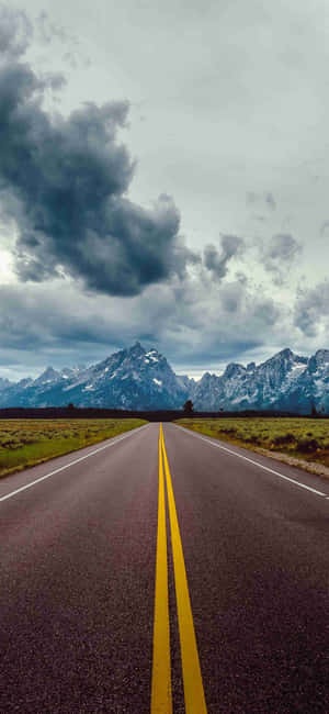 Mountain_ Road_ Under_ Stormy_ Skies Wallpaper