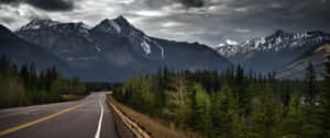 Mountain_ Road_ Under_ Stormy_ Skies Wallpaper