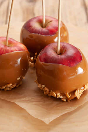 Mouth-watering Caramel Apples On A Rustic Wooden Table Wallpaper