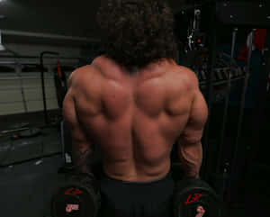 Muscular Man Performing Dumbbell Workout Gym Wallpaper