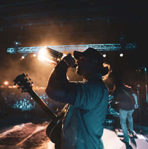 Musician Drinking Onstage During Concert Wallpaper