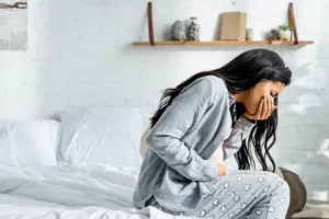 Nauseous Pregnant Woman On Bed Wallpaper