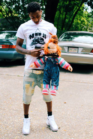 Nba Youngboy Poses With Signature Chucky Doll Wallpaper