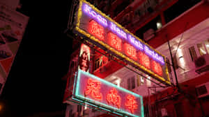 Neon Signs Aglow Against Night Sky Wallpaper