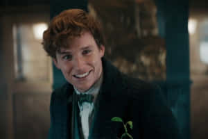 Newt Scamander Smilingwith Plant Wallpaper