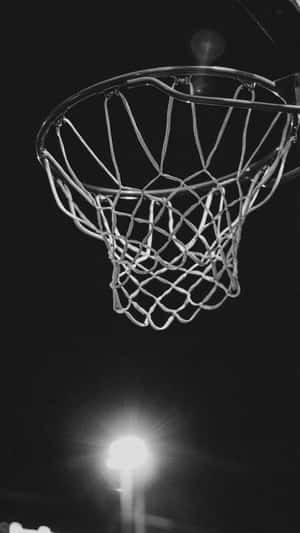 Nighttime Basketball Hoop Under Lights Wallpaper