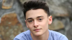 Noah Schnapp Against Rock Wall Wallpaper