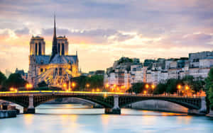 Notre Dame Cathedral With Bridge Lit With Orange Lights Wallpaper