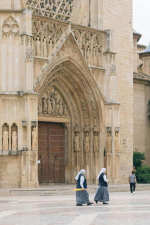 Nuns_ Walking_ By_ Gothic_ Church Wallpaper