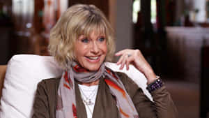 Olivia Newton John Smiling During Interview Wallpaper