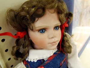 Ornery Doll With Red Ribbon In Hair Wallpaper