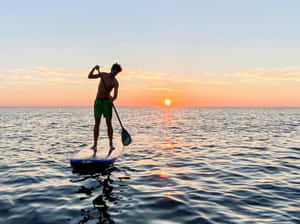 Paddleboarding At Sunset Wallpaper