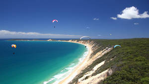 Paragliding Above Colossal Slanted Cliff Wallpaper