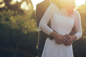 Photo Of A Couple's Tangible Hug Wearing White Dress And Black Suit Wallpaper