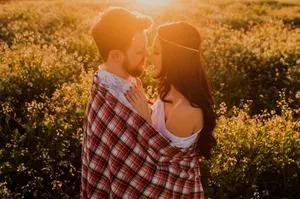 Picture Of A Couple Tangible Facing Each Other Closely On A Flower Field Wallpaper