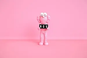 Pink Kaws Figure Holding Sign Wallpaper