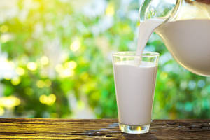 Pitcher Filling Up Glass With Milk Wallpaper