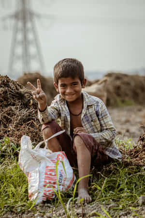 Poor Boy Sitting Down Doing A Peace Sign Wallpaper