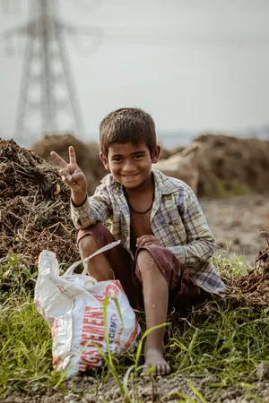 Poor Boy Sitting Down Doing A Peace Sign Wallpaper