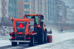 Powerful Snowplow Clearing A Road In Winter Wonderland Wallpaper