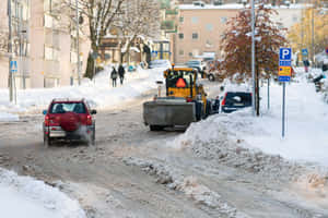 Powerful Snowplow Clears A Snowy Road Wallpaper