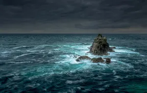 Powerful Waves Crashing Against Rocky Shoreline During A Raging Ocean Storm Wallpaper