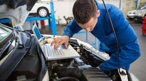 Professional Mechanic Performing Car Repair Wallpaper