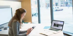 Professional Woman Using Smartphoneat Work Desk Wallpaper