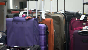 Purple Suitcase Among Othersat Airport Wallpaper