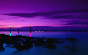 Purple Sunset Hues Over Tranquil Shore Wallpaper