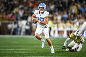 Quarterback Evading Tackle During Game.jpg Wallpaper