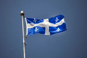 Quebec Fleurdelis Flag Against Blue Sky Wallpaper