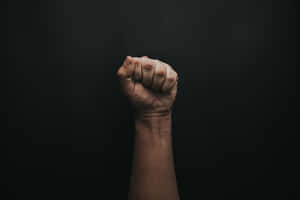 Raised Fist Against Black Background Wallpaper