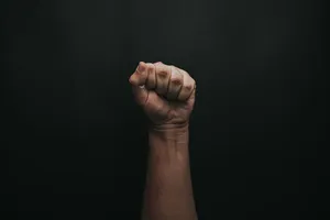 Raised Fist Against Black Background Wallpaper