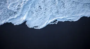 Relax On The Tranquil Black Sand Beach Wallpaper