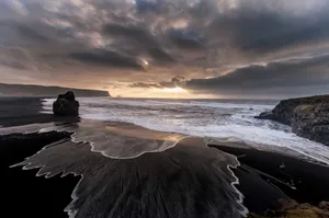Relaxing On A Dramatic Black Sand Beach Wallpaper