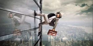 Resilient Man I Suit And Tie Soaring Above A Building Wallpaper