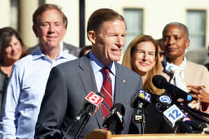 Richard Blumenthal Talking Into A Bunch Of Microphones Wallpaper