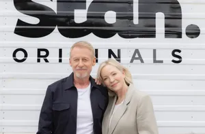 Richard Roxburghand Costar Smile Beside Studio Originals Sign Wallpaper