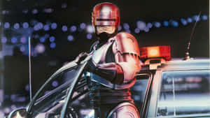 Robocop Standing By Police Car Wallpaper